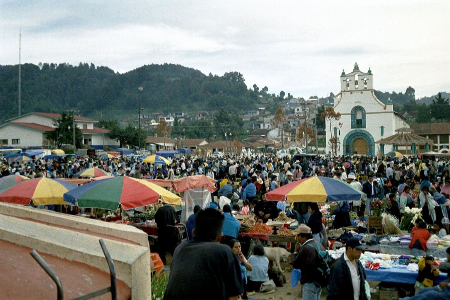 Piazza del mercato di San Juan Chamula con bancarelle colorate e persone, in una fotografia del 2003.