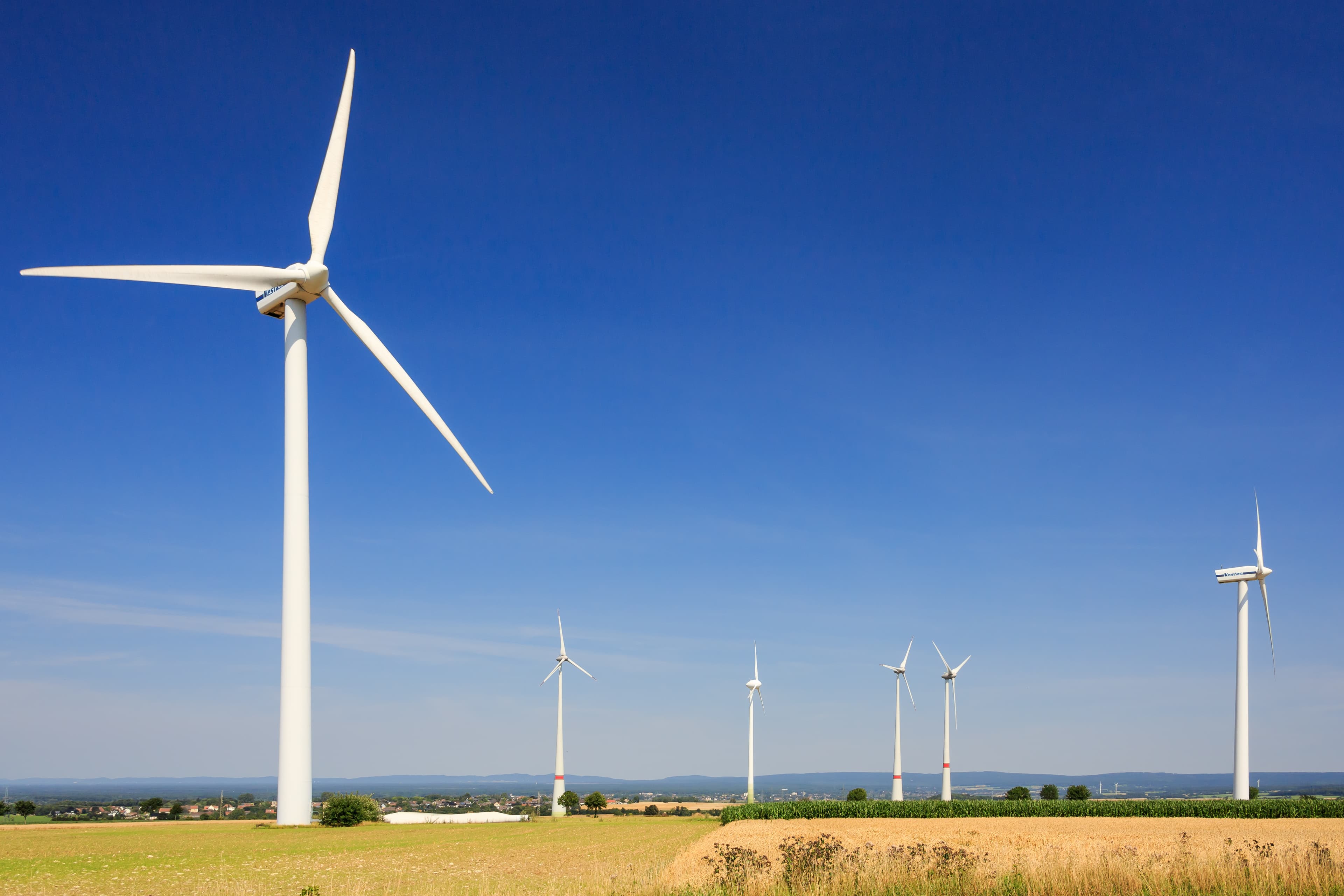 Turbine eoliche bianche tra i campi di Paderborn, sotto un cielo azzurro.