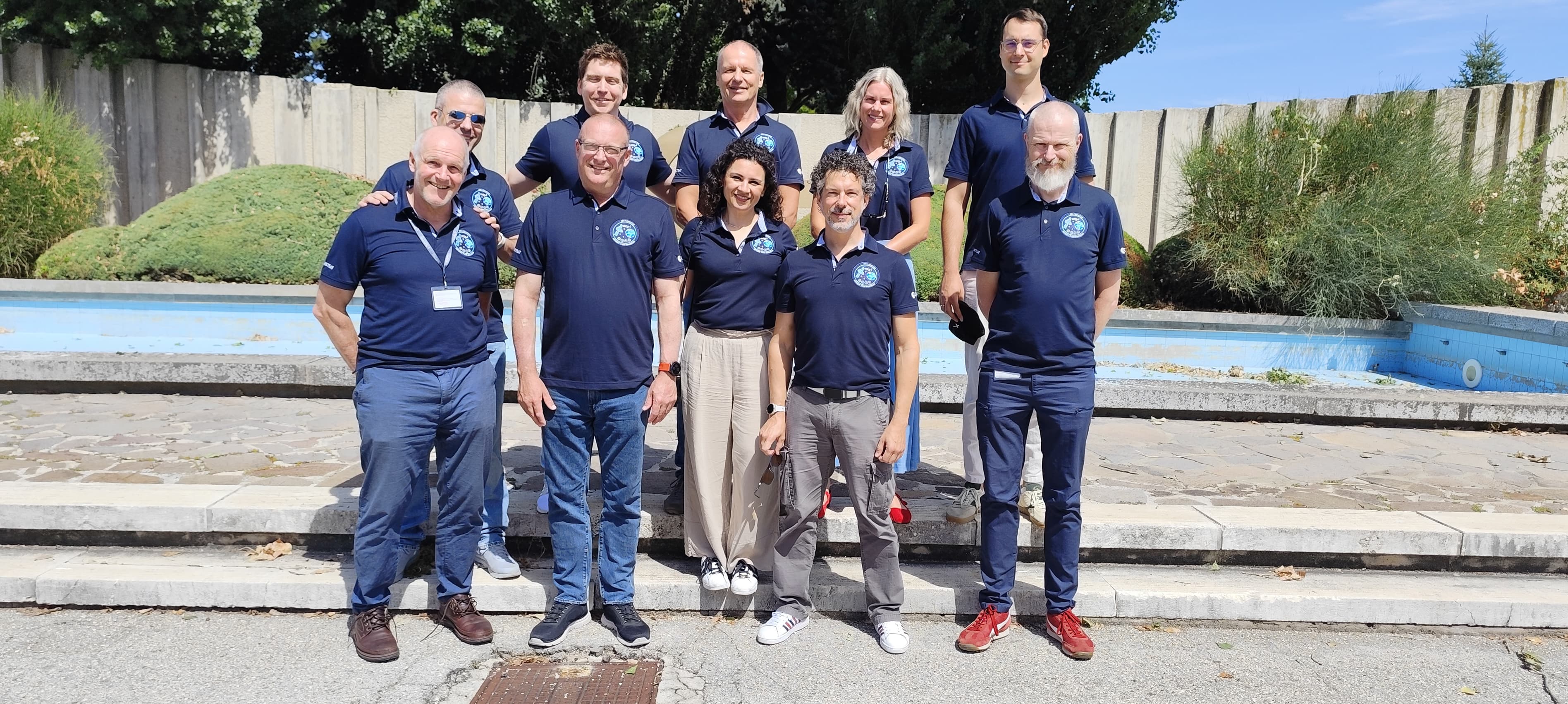 Membri della squadra ESA di MTG-I2 posano all’aperto con polo blu davanti a una vasca.