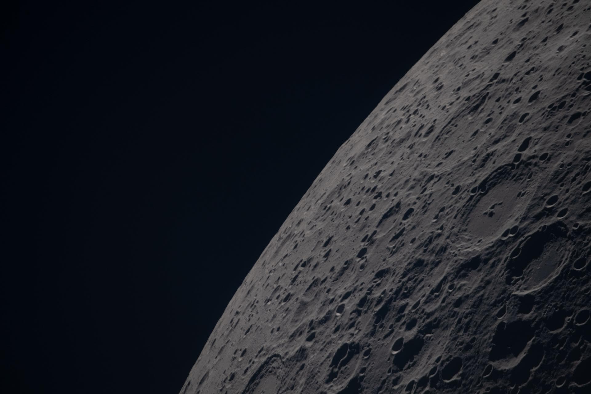 Superficie craterizzata della faccia nascosta della Luna accanto al nero dello spazio.