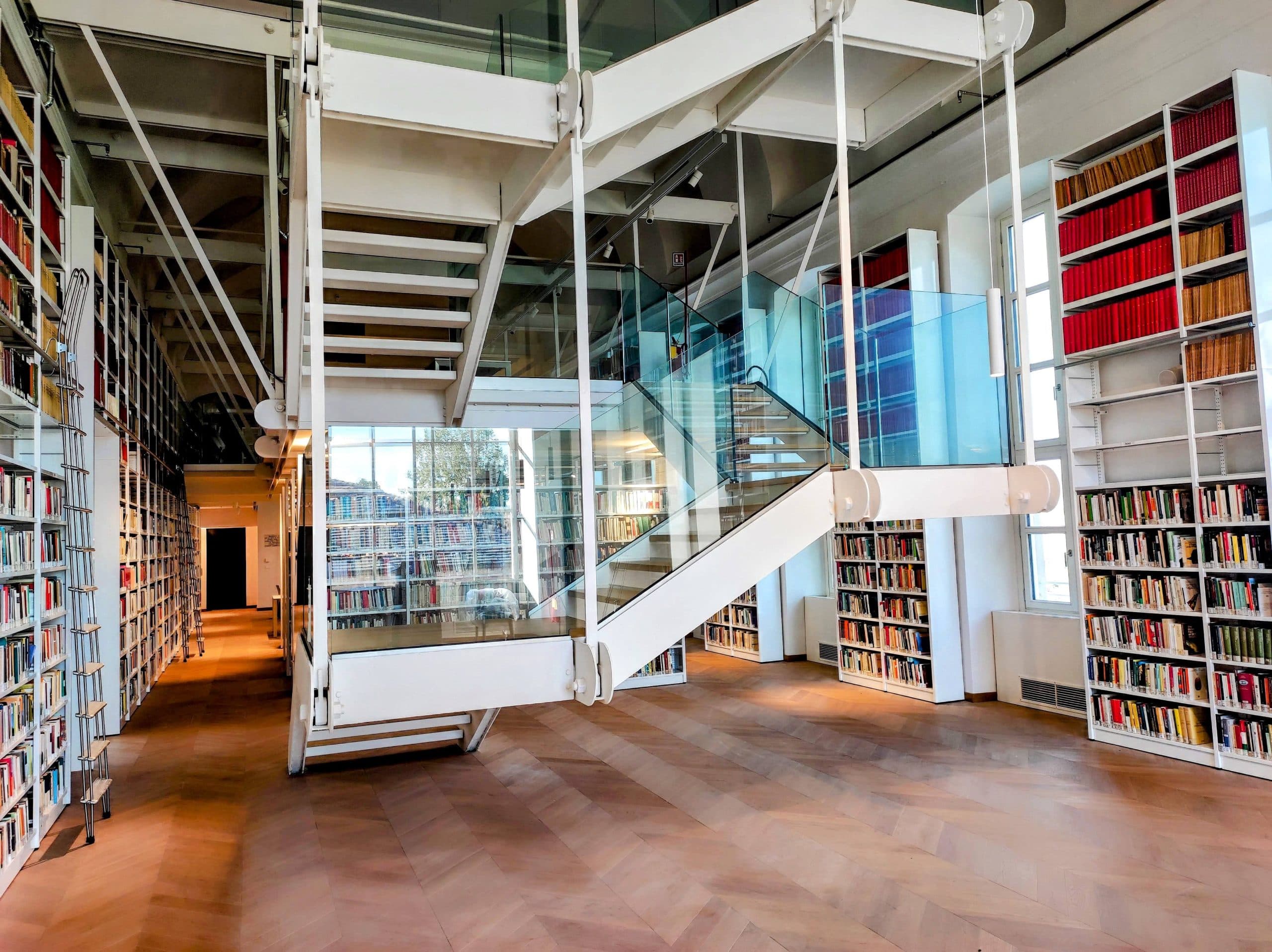 Scaffali di libri, scale bianche e parapetti in vetro negli spazi del polo ESSECI