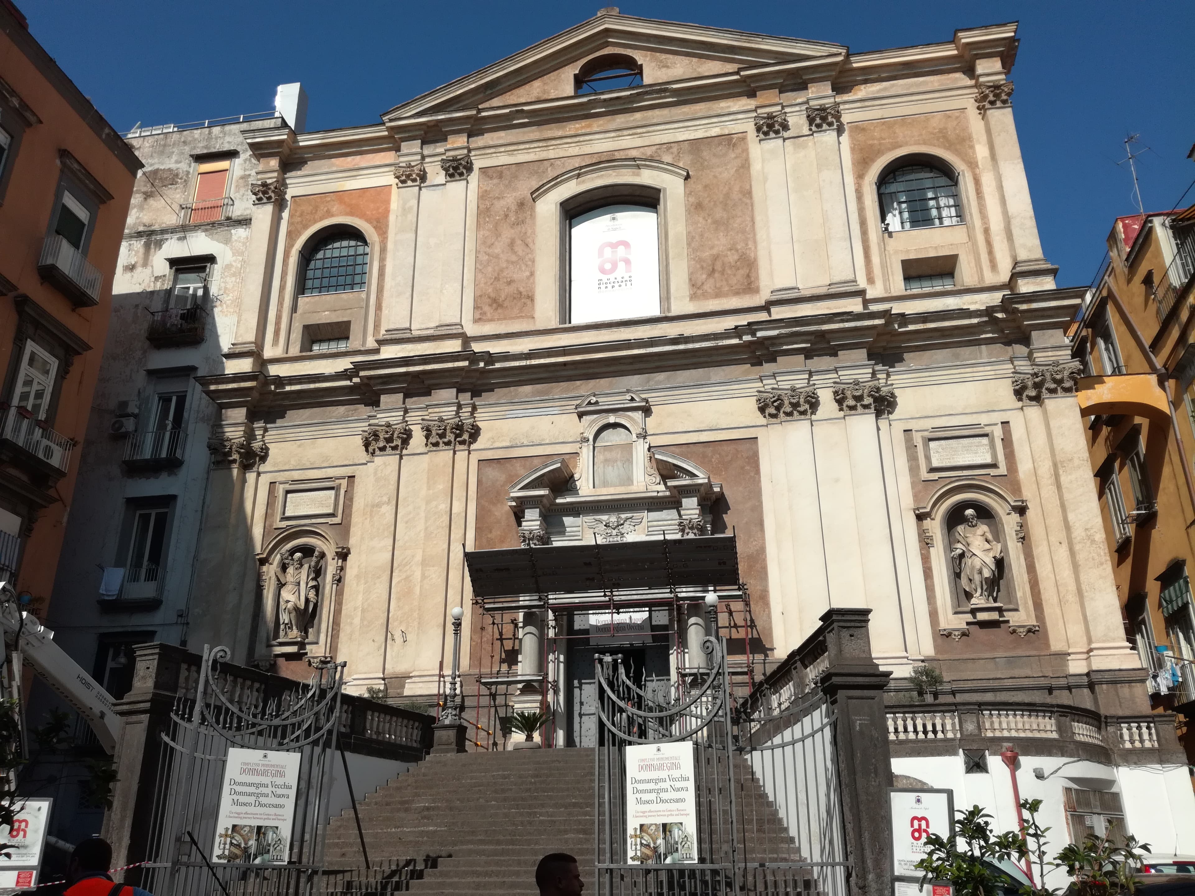 Facciata di Donnaregina Nuova a Napoli, con statue nelle nicchie, scalinata e cancello d’ingresso.