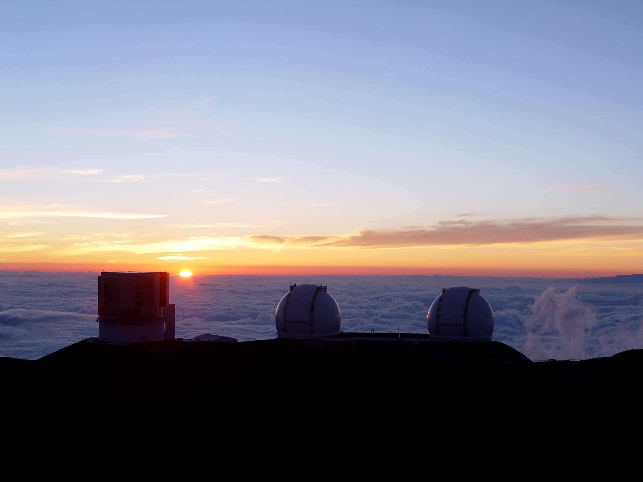 Gli edifici dei telescopi Subaru e Keck al tramonto, sopra le nuvole.