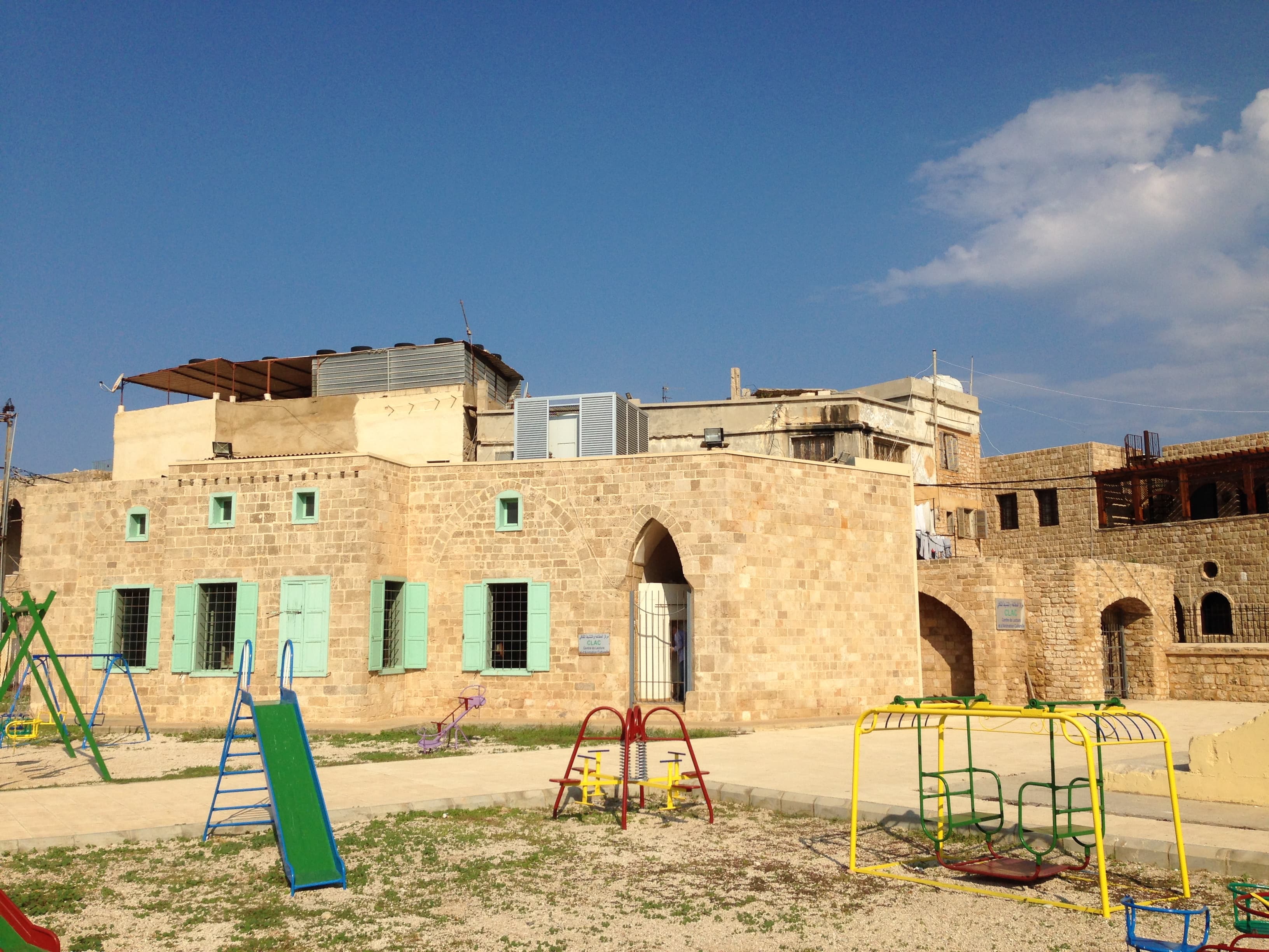 Edificio in pietra del centro di lettura di Tiro, con persiane verdi e giochi nel cortile