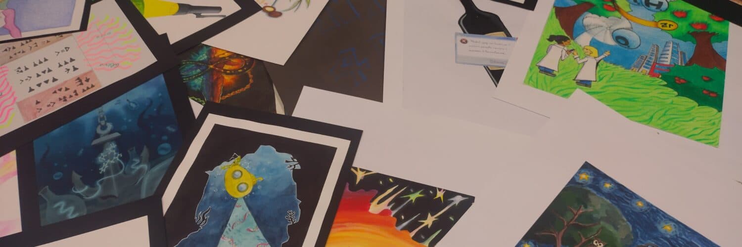 Disegni di studenti su temi scientifici disposti su un tavolo