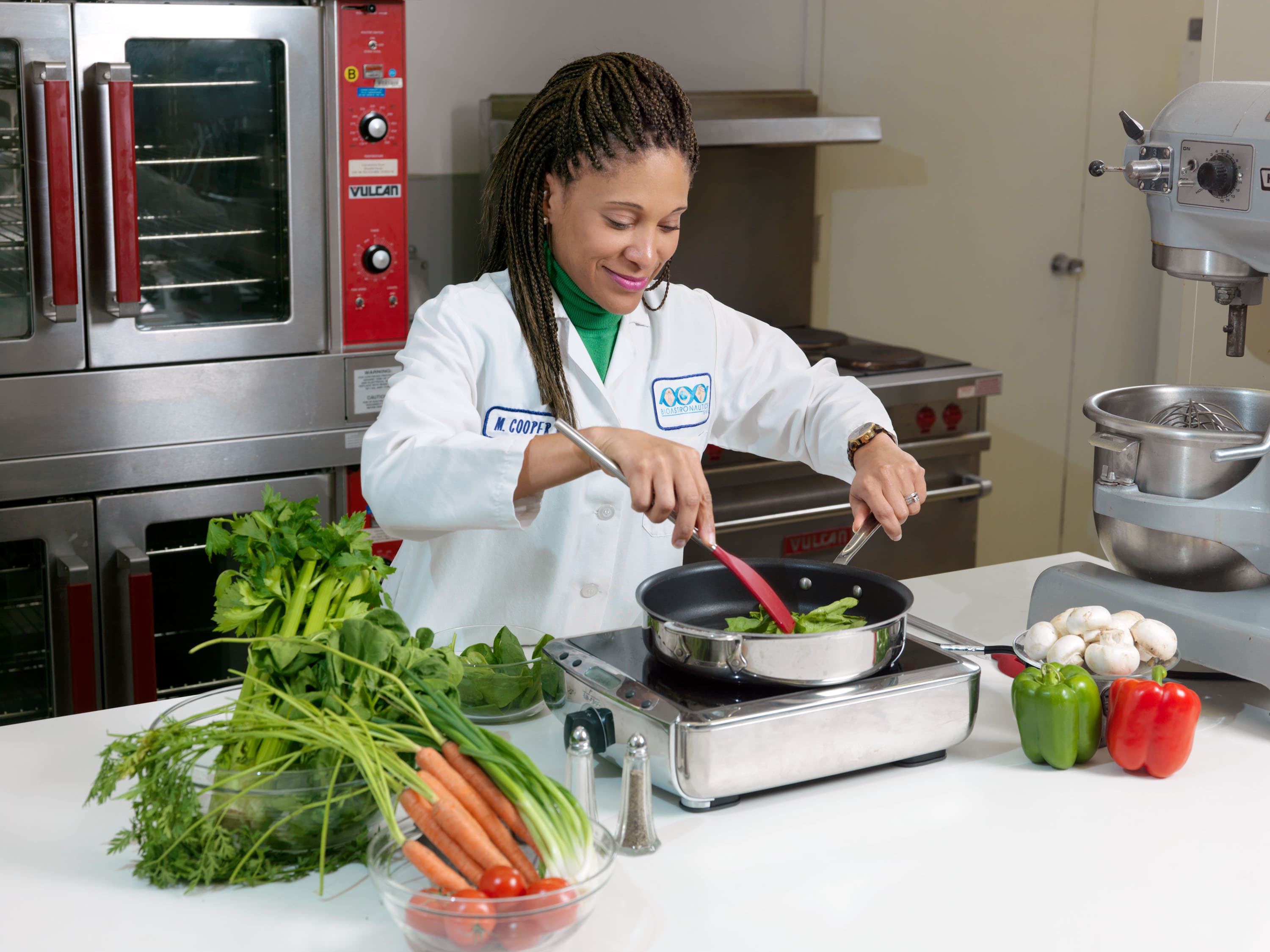 Una ricercatrice prepara verdure in padella in una cucina di laboratorio NASA.