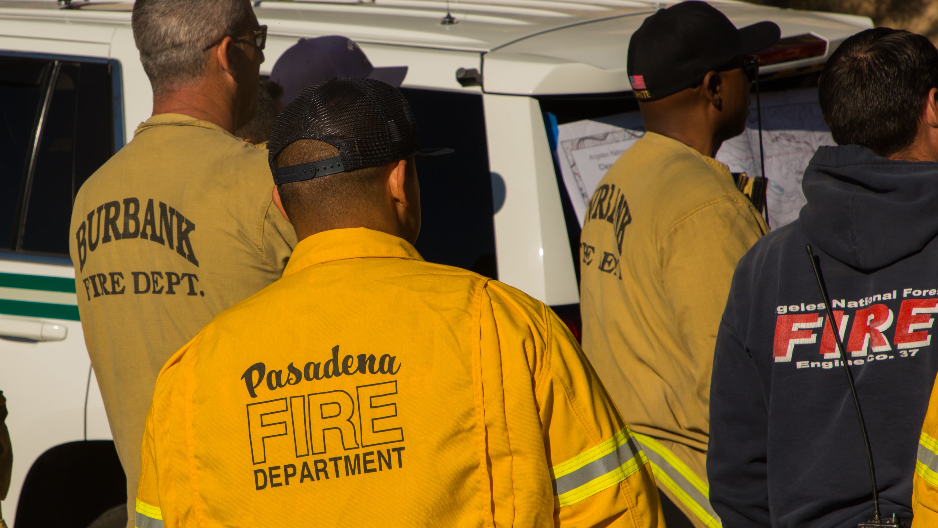 Operatori antincendio di reparti diversi consultano una mappa accanto a un veicolo.