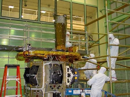 Tecnici in tute bianche accanto a Swift e al suo telescopio UVOT in una sala di integrazione.