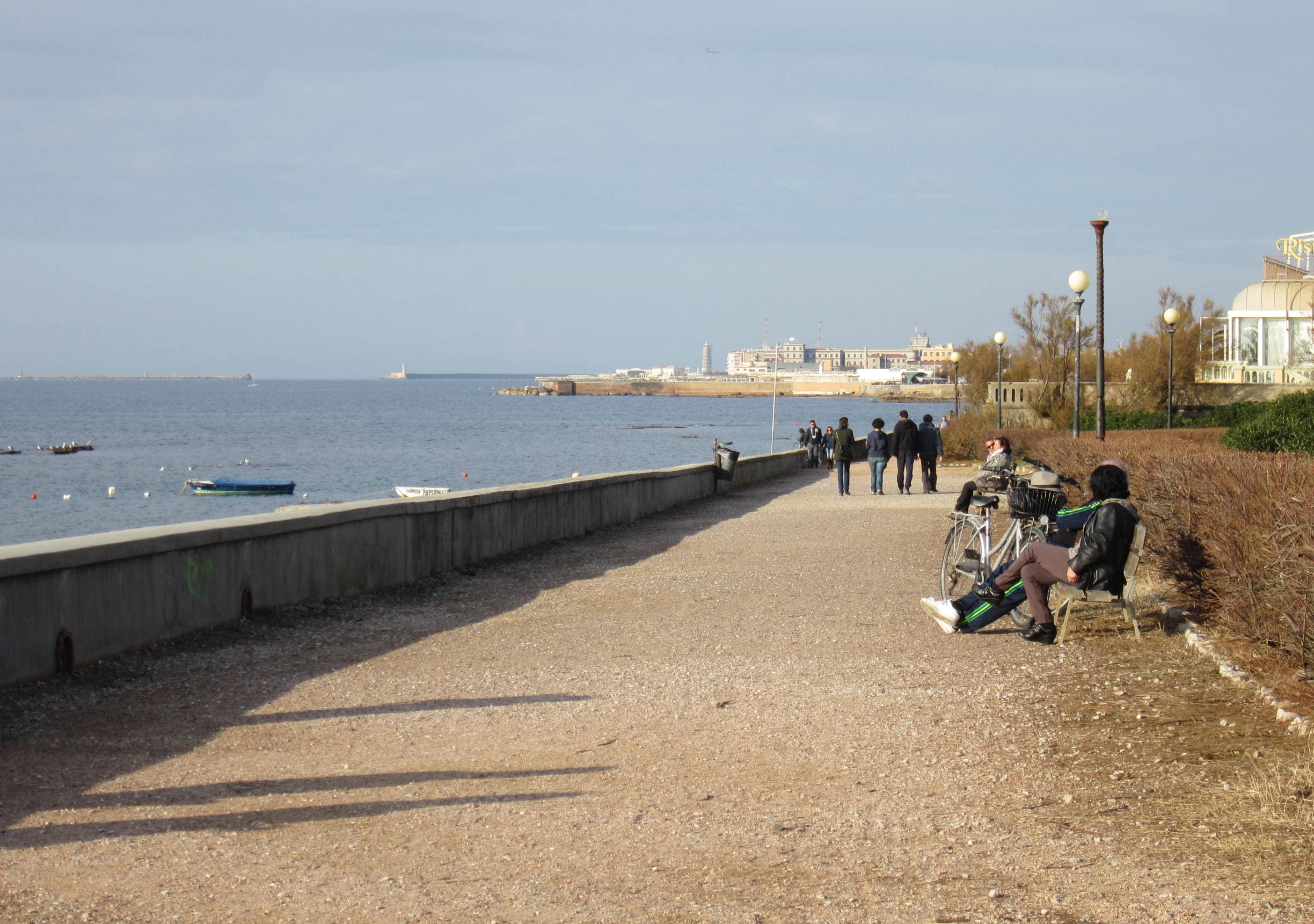 Passeggiata sul mare ad Antignano, con persone a piedi, panchine e biciclette.