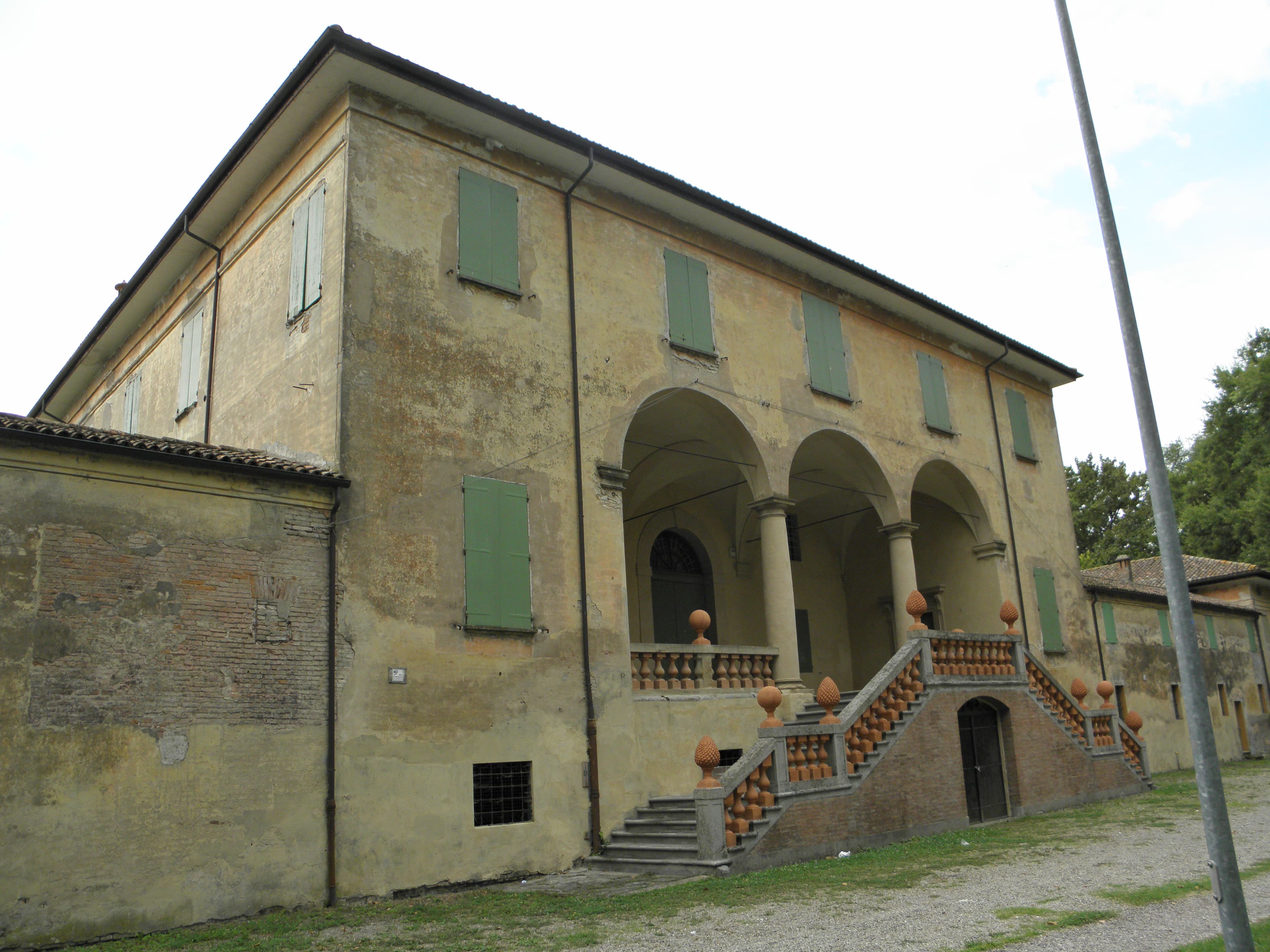 Façade de Villa Beatrice avec un portique à trois arches, un escalier extérieur et des volets verts.