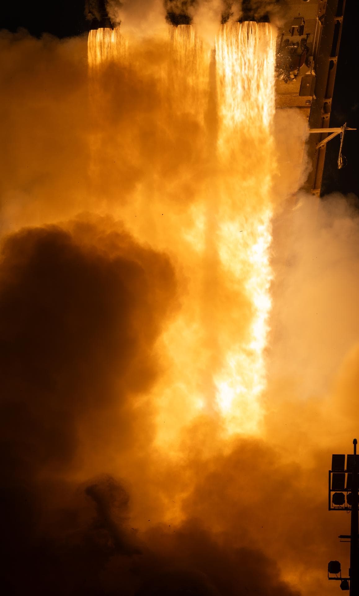 Getti luminosi e nubi di gas sotto i motori del Falcon Heavy durante il lancio del telescopio Roman.