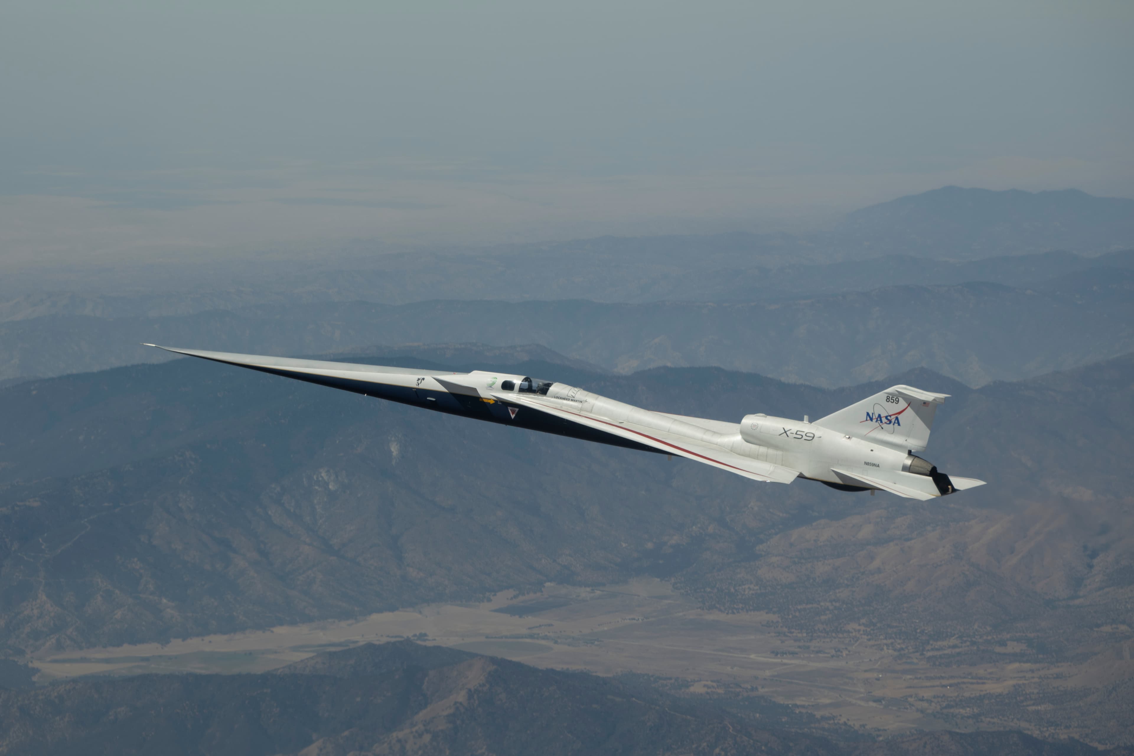 L’aereo sperimentale X-59, bianco e dal muso molto allungato, in volo sopra il deserto del Mojave.