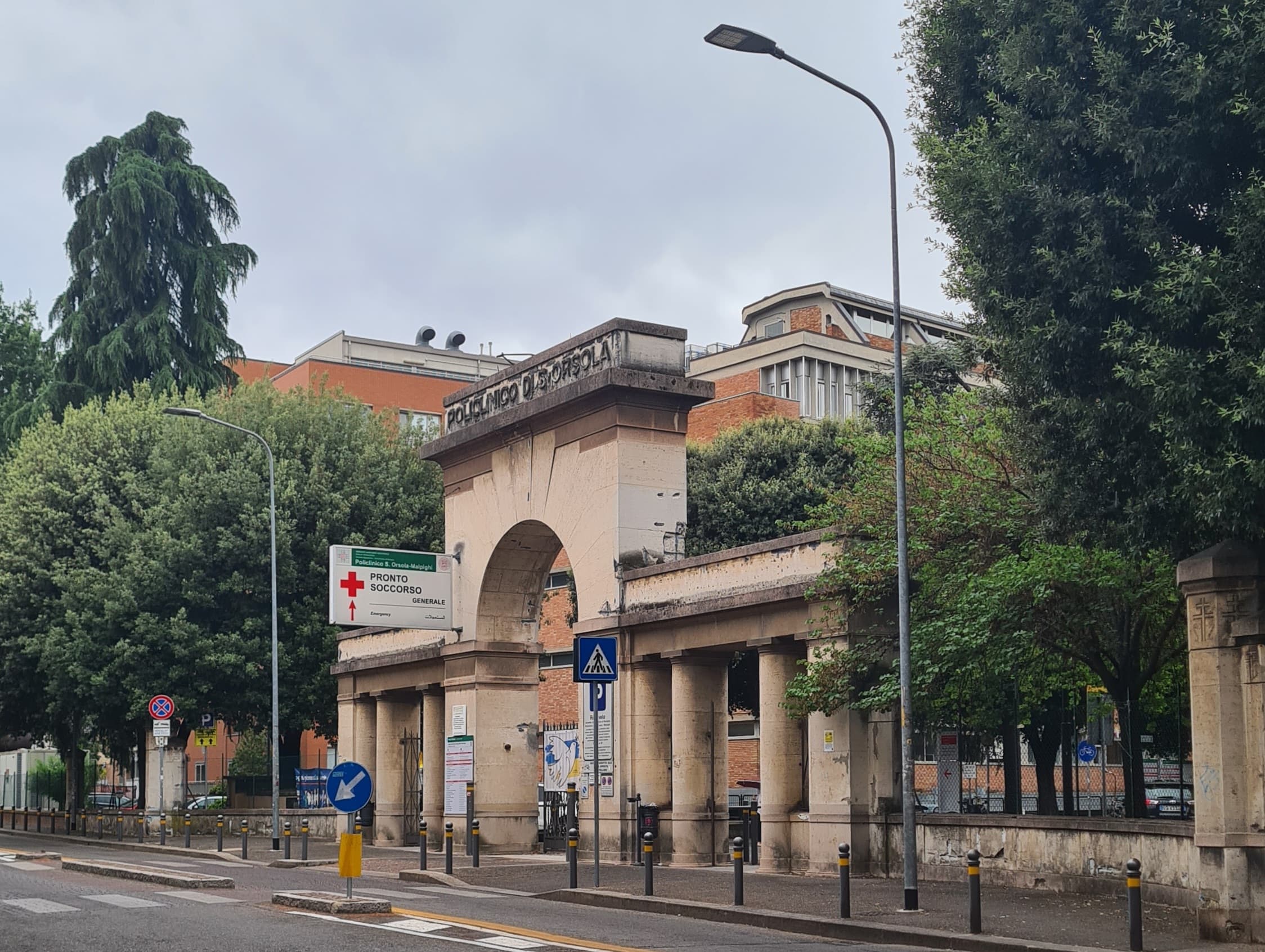 Ingresso del Policlinico Sant’Orsola su via Albertoni a Bologna, fra alberi e segnaletica.