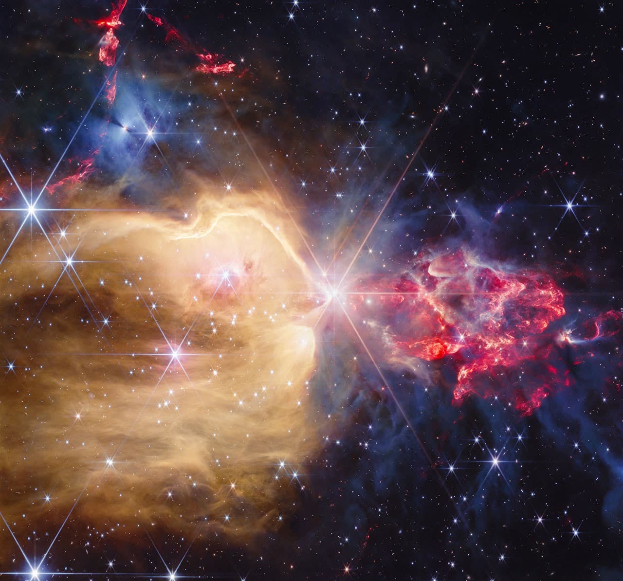 Nebulosa NGC 7129 osservata da Webb, con una stella luminosa e strutture dorate e rosse.
